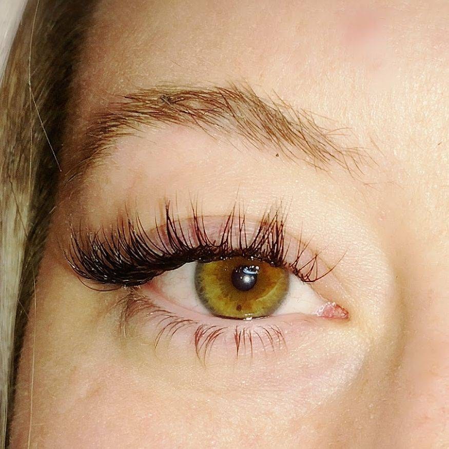 A Jumeaux lash artist applying individual eyelash extensions to a reclining guest in a bright private suite